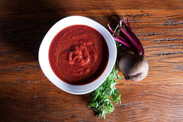 Nutrition concept - Healthy meals in White bowls over wooden background. Healthy food, Diet, Detox, Clean Eating or Vegetarian concept. Delicious soup made of beetroot.