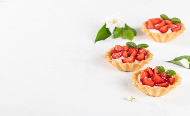 Dessert tartlets with vanilla cream and strawberries on a white background copy space