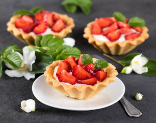 Tartlets with custard and fresh strawberries on a dark background
