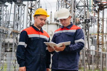 Two specialist electrical substation engineers inspect modern high-voltage equipment. Energy. Industry