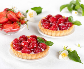 Tartlets with custard and fresh strawberries on a white background