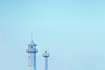 Minimalistic picture of lighthouse on blue background. Wallpaper with tower in the sky.