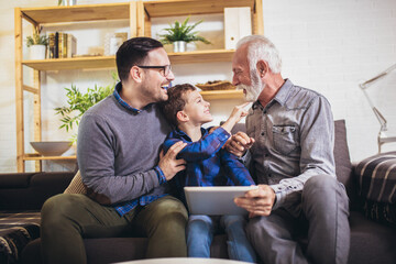 Portrait of a three generation family spending time together at home using digital tablet.