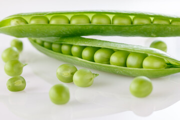 Pods of green peas with pea leaves and flowersd on a white background. Organic food.