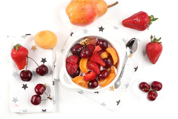 Fruit salad, Healthy breakfast with ingredients, yogurt with granola, strawberries, cherries and peaches on a light table. The concept of healthy and natural food, lifestyle. selective focus