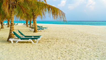 Fototapeta na wymiar Lounge chairs on a beautiful tropical beach at Maldives