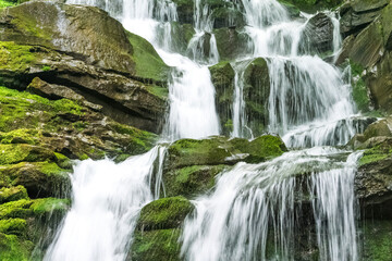 Obraz premium Wodospad spadający z wysokiego klifu w górach.