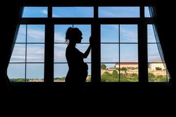 Silhouette of a pregnant woman by the window