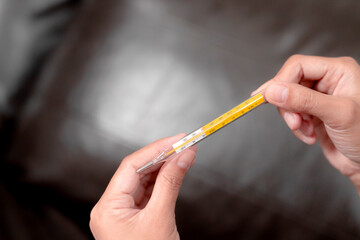 A woman's hand holding a thermometer.