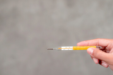 A woman's hand holding a thermometer.