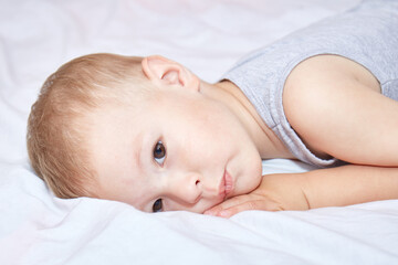 Toddler thought lying on a white bedspread