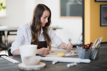 Woman's fingers adding and adjusting a clay part on a future ceramic product.