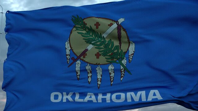 Flag of Oklahoma waving in the wind against deep beautiful clouds sky