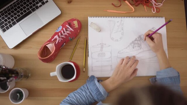 Top desk view of designer working on customizing sneakers sketch