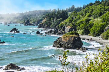 Moss covered rocks jutting out of the ocean Trinidad Bay in Northern California with fog over...