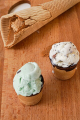 Craft mint and vanilla flavor ice-cream in waffle cups glazed with chocolate wooden board. High quality photo