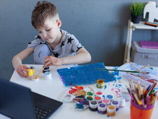a boy in front of a laptop learns to paint