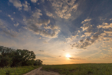 Fototapeta na wymiar Cloudy sunset over fields summer evening photo