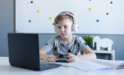 boy in front of laptop sits in headphones, online learning concept