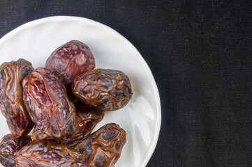 Big luxury dried date fruit in bowls on the dark surface, kurma ramadan kareem concept, close up.