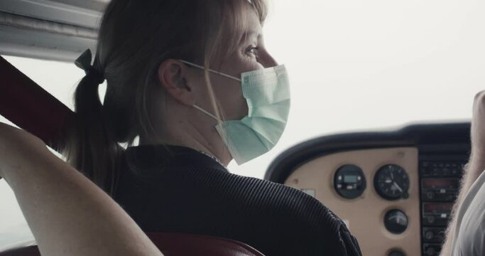 Woman showing passenger with face masks in cockpit of small airplane plane aircraft to look out flying flight on staycation local travel virus covid 19 coronavirus pandemic outbreak new normal