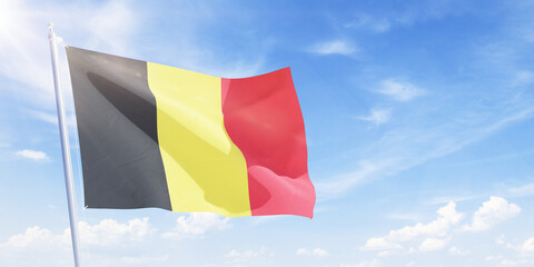 Belgium flag on a flagpole waving in blue cloudy sky. Belgium concept 3D rendering