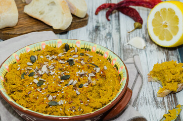 Red lentil hummus in a clay bowl on a rustic background. Lebanese appetizer