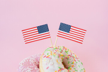 Two mini american flags of toothstick stuck top in donuts on pink background. 4th of july, happy usa independence day. Celebration memorial day in America. Copy space for text.