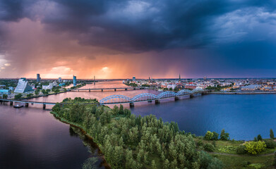 Fototapeta na wymiar Aerial view of iconic Riga city downtown in dramatic sunset. Modern architecture in rainy weather with storm clouds in warm colors. 