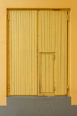 Fototapeta na wymiar The wall and large double wooden doors are painted yellow