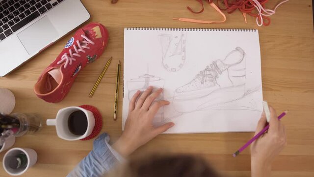 Woman designer using rubber to correct mistakes on fashion sketch