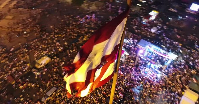 Beirut, Lebanon 2019 : night drone shot of Martyr square, turn around the Lebanese flag in foreground, with thousands of protesters revolting against government failure during the Lebanese revolution