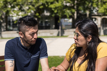 couple of man and woman sitting on a bench outdoors