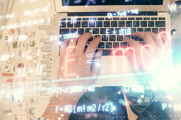 Double exposure of man's hands typing over computer keyboard and formula hologram drawing. Top...