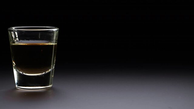 A shot of alcohol slides into frame leaving negative space.  No people.  In 4K slow motion at 60 fps.