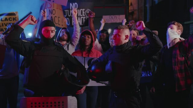 Black lives matter. Two cops support the protest holding their helmets strike among group of activists. Multi-ethnic protesters rebel against violence, inequality, racism.