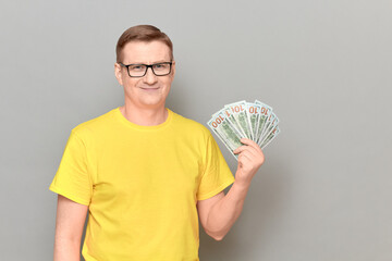 Portrait of happy cheerful mature man holding money and smiling