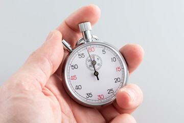 Man holding analoguel stopwatch on the gray background.