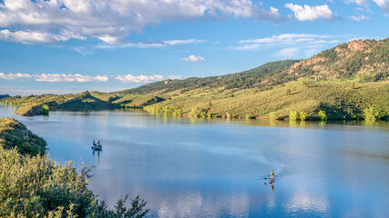 summer morning on  Horsetooth Reservoir at foothills of Rocky Mountains in northern Colorado with a fishing boat and a stand up paddler, popular recreation destination in Fort Collins area