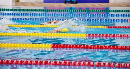 Young boy swimming Freestyle posture in the blue water pool.