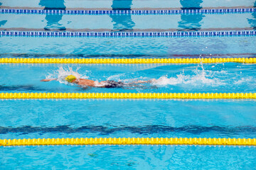 Young boy swimming Freestyle posture in the blue water pool.