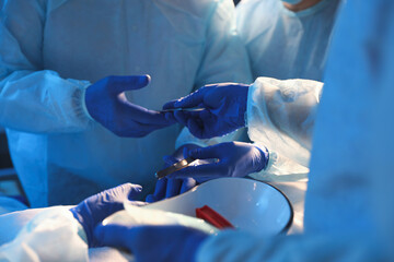 Team of professional doctors performing operation in surgery room, closeup