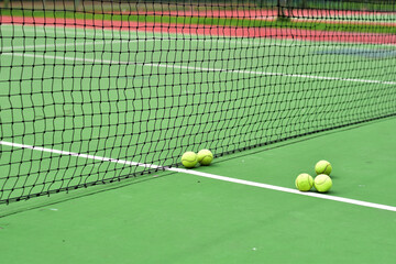 Closeup of Tennis Racket and balls on Tennis Courts in the outdoors.