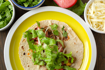 Yellow plate with mexican speciality beef tacos on a wooden table