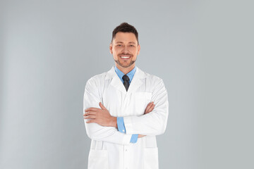 Happy man in lab coat on light grey background