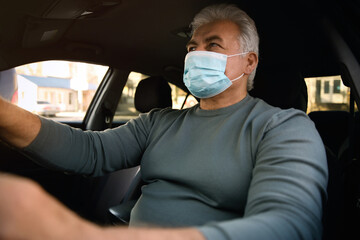 Senior man with medical mask in car. Virus protection