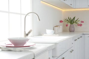 Fototapeta na wymiar Beautiful ceramic dishware and bouquet on countertop in kitchen
