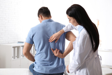 Professional orthopedist examining man in medical office
