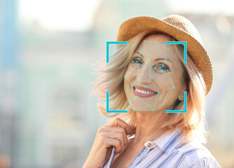 Facial recognition system. Mature woman with scanner frame and digital biometric grid, outdoors