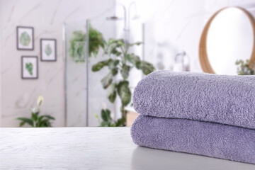 Fresh towels on white wooden table in bathroom. Space for text